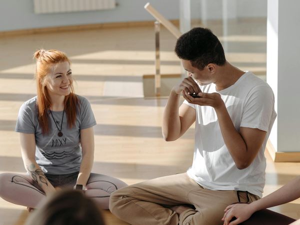 A group of diverse people practicing yoga together in a bright, sunlit studio.